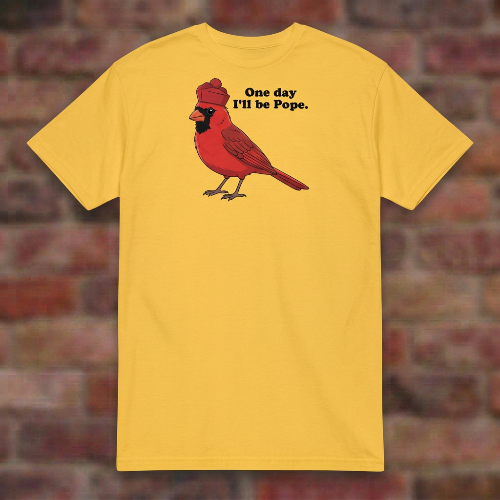 One day I'll be Pope T-shirt in Daisy, flat lay on blurred brick