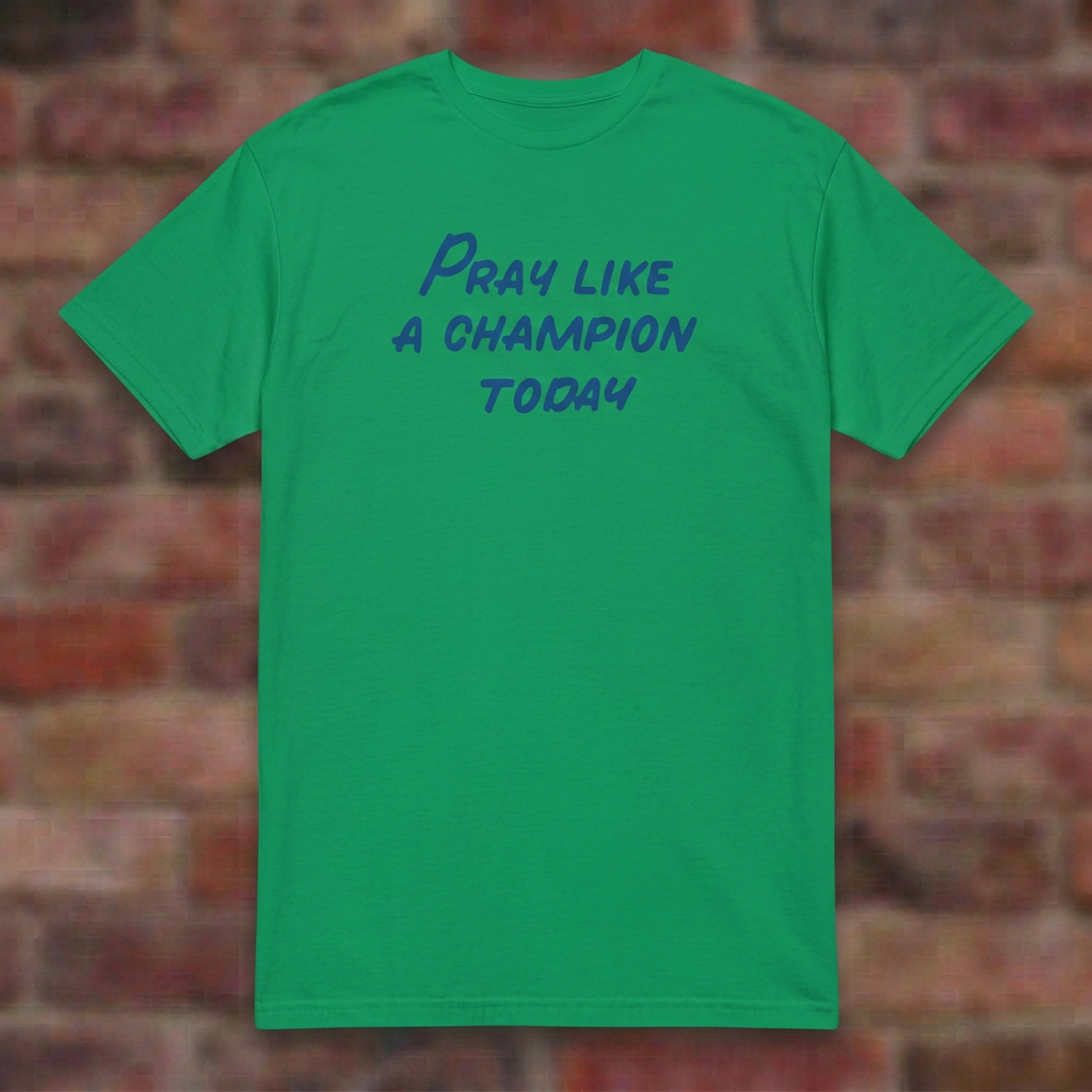Pray Like a Champion T-shirt in Irish Green, flat lay on blurred brick