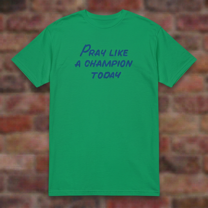 Pray Like a Champion T-shirt in Irish Green, flat lay on blurred brick