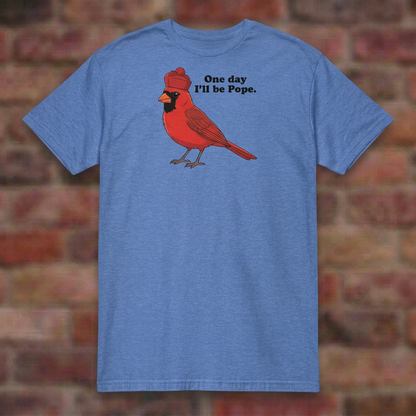 One day I'll be Pope T-shirt in Heather Royal, flat lay on blurred brick